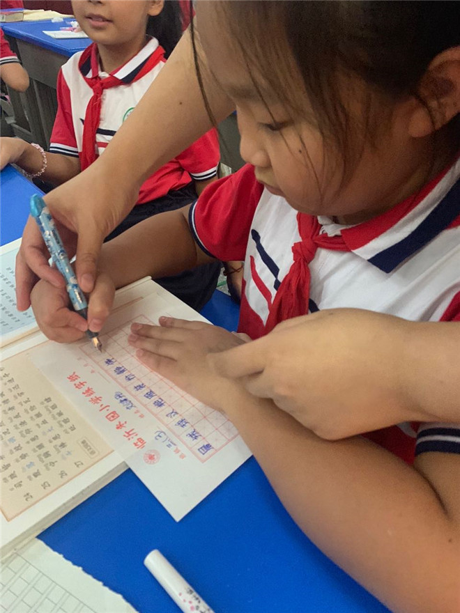 老师在指导学生拿笔姿势.jpg